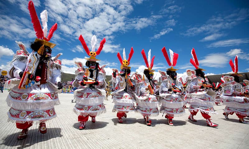pessoas com adornos brancos e vermelhos desfilando em Puno