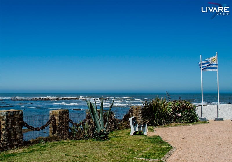 paisagem com banco e bandeira do uruguai com mar ao fundo