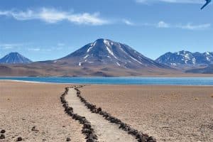 caminho de pedras em meio ao deserto com vulcão e montanhas ao fundo