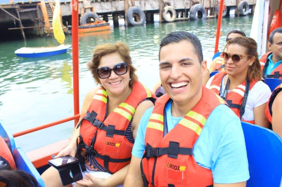 homem e mulher vestindo colete salva-vidas sorrindo para a câmera em passeio em grupo de barco