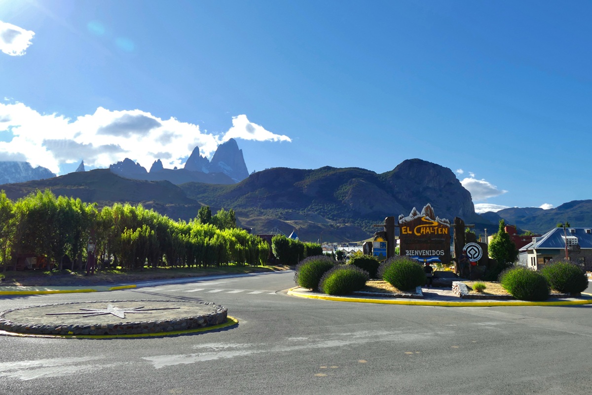 Entrada da vila de El Chaltén com placa de boas-vindas e montanhas ao fundo, incluindo o Monte Fitz Roy na Patagônia Argentina