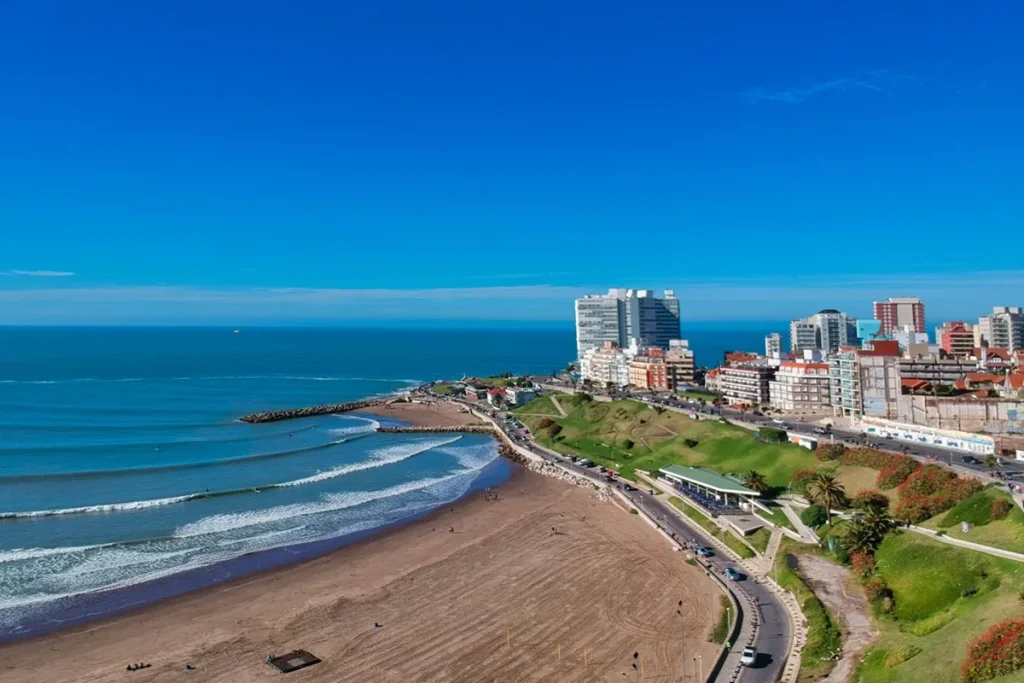 Vista aérea da praia de Mar del Plata com edifícios modernos à beira-mar e ondas suaves no oceano