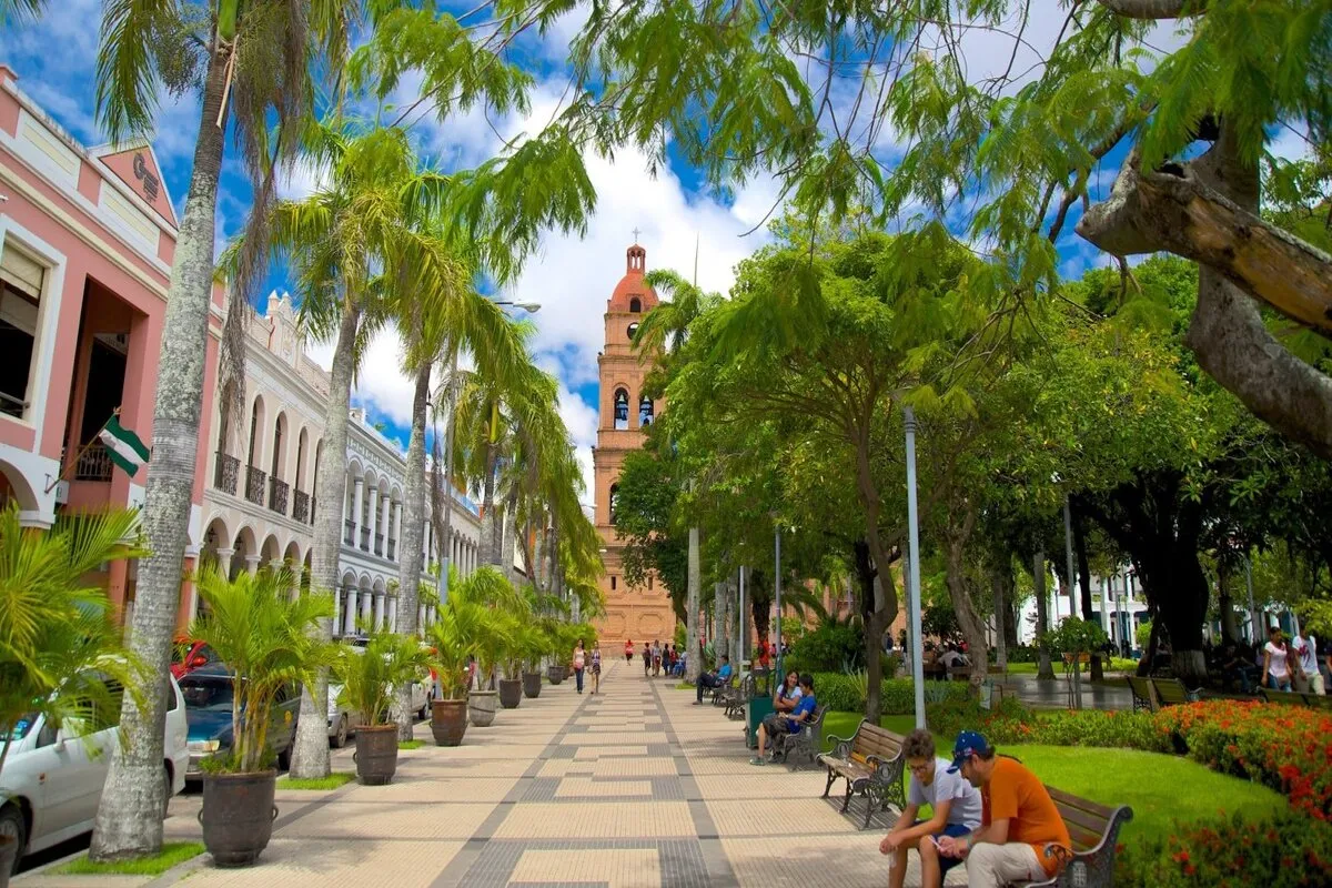 Praça arborizada com catedral ao fundo em Santa Cruz de la Sierra, Bolívia.