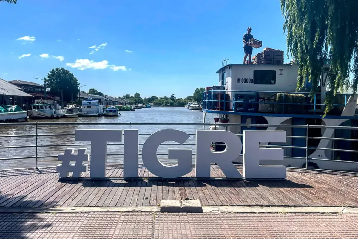 Letreiro #TIGRE em frente ao rio em Tigre, Argentina, com barcos atracados ao fundo