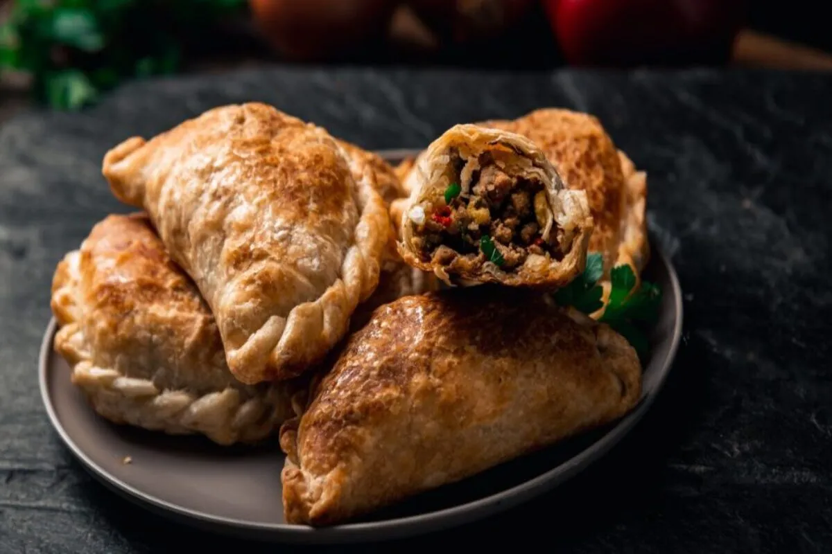 Empanadas argentinas assadas com recheio de carne moída, pimentões e especiarias em prato rústico