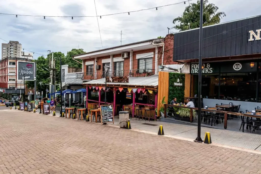 Ruas com restaurantes e barracas da Feirinha de Puerto Iguazú na Argentina, com mesas ao ar livre e decoração colorida