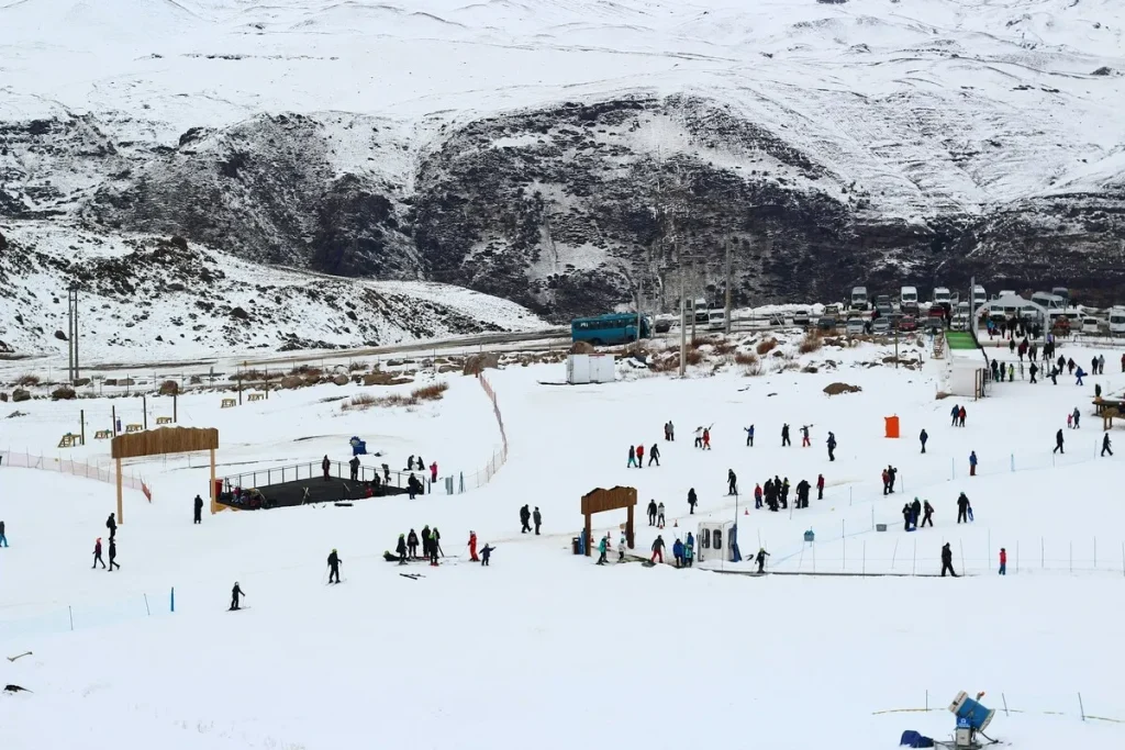 Estação de esqui no Chile com pessoas praticando esportes na neve em um cenário montanhoso