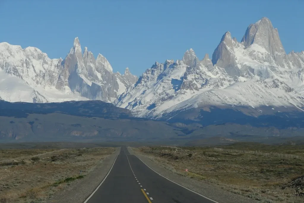 Estrada reta na Patagônia com montanhas nevadas ao fundo