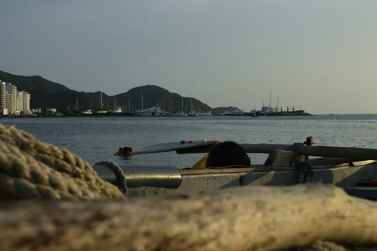 Vista do mar e da costa de Santa Marta, Colômbia, com barcos no porto e montanhas ao fundo, sob o pôr do sol, representando a beleza do porto de Santa Marta.