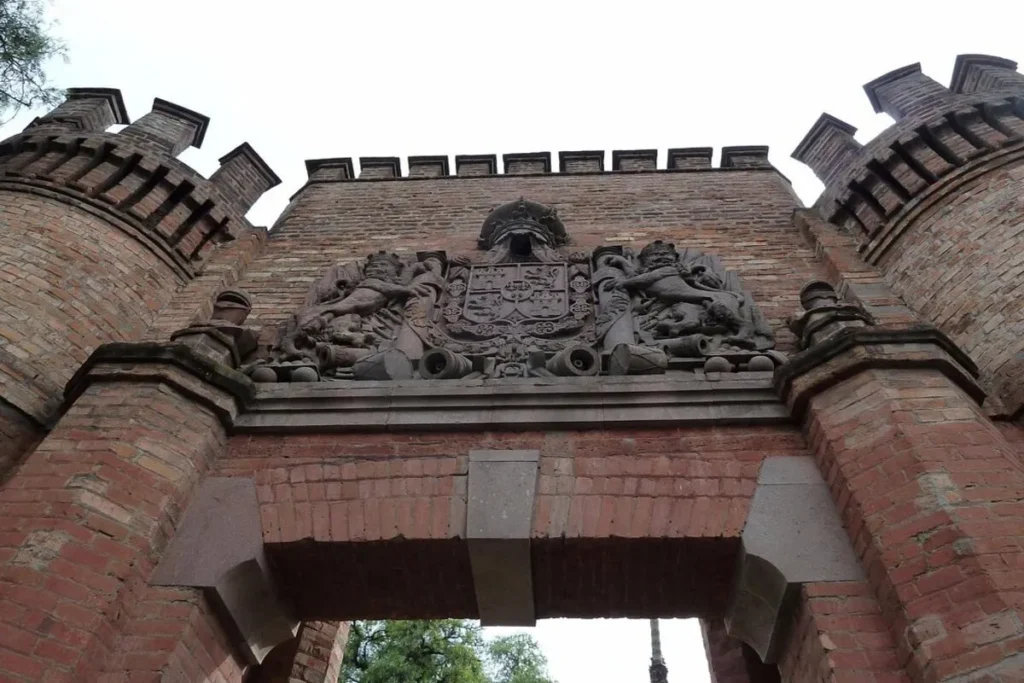 A entrada de tijolos e pedra do Cerro Santa Lucía em Santiago, com um arco e um brasão esculpido e duas torres.