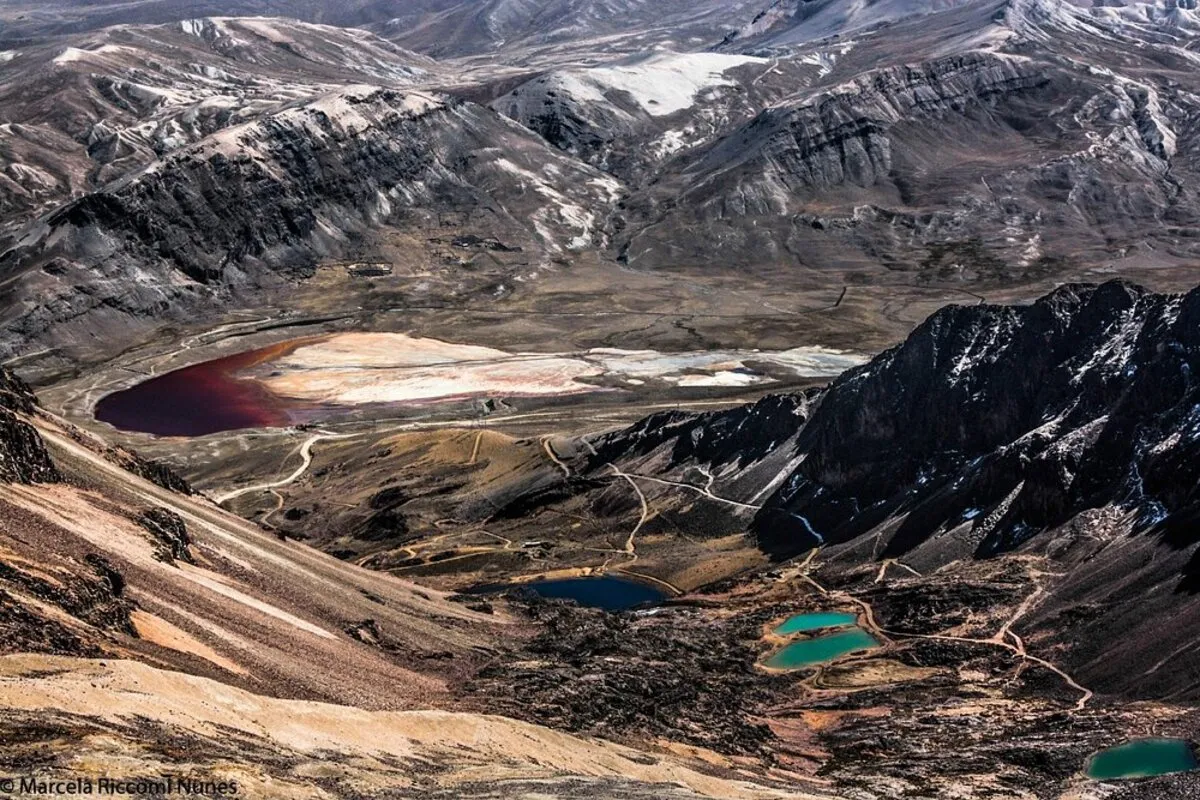 Vista do pico de Chacaltaya, na Bolívia, com montanhas e lagos alpinos em um dia de céu azul.