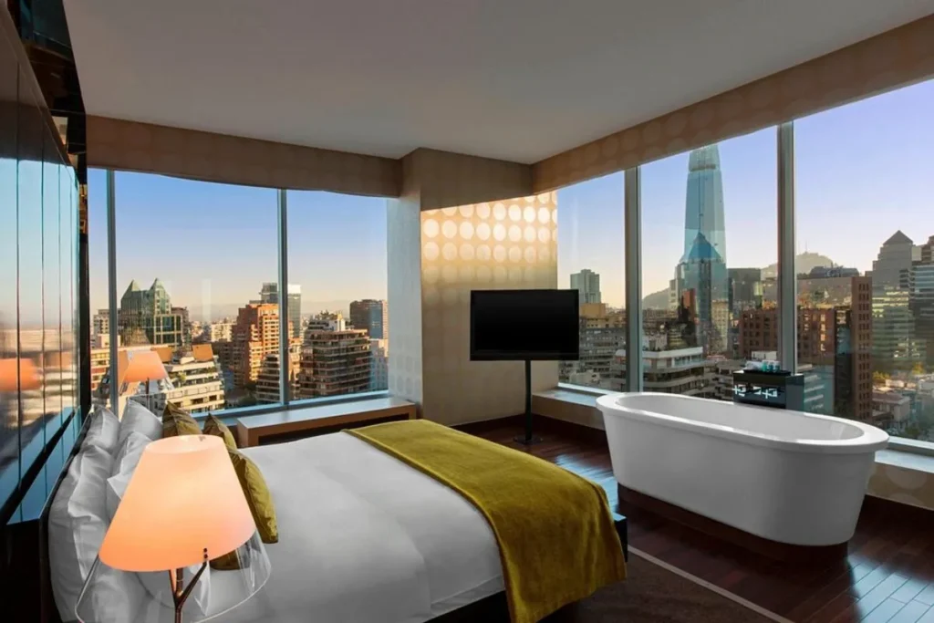 Quarto de hotel de luxo no W Santiago Hotel, com cama king-size, banheira, TV e vista panorâmica da cidade.
