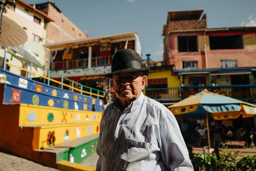 Homem com chapéu preto em frente às escadarias coloridas de Guatapé, Colômbia.