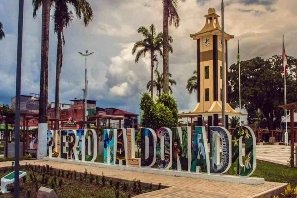 Plaza de Armas de Puerto Maldonado com letreiro colorido e torre do relógio ao fundo.