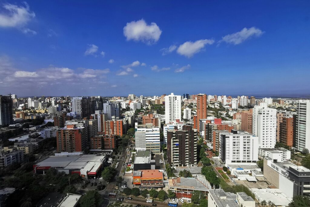 Vista panorâmica de Barranquilla com prédios residenciais e comerciais sob céu azul em dia ensolarado.
