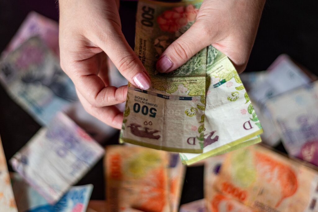 Pessoa contando notas de peso colombiano, moeda oficial da Colômbia, durante planejamento financeiro de viagem para Barranquilla.