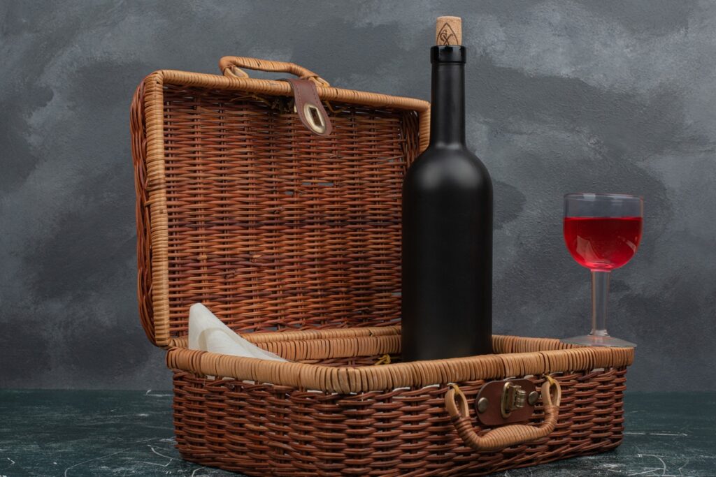 Cesta de piquenique aberta com garrafa de vinho e taça, representando o transporte de bebidas em viagem.