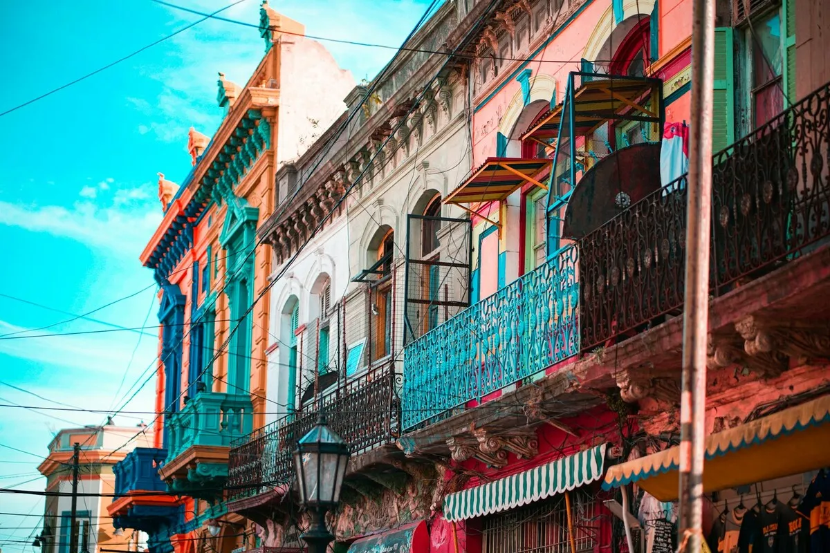 Casas históricas coloridas e vibrantes, com sacadas de ferro forjado e tons de azul, vermelho, rosa e verde-água, em La Boca, Buenos Aires.