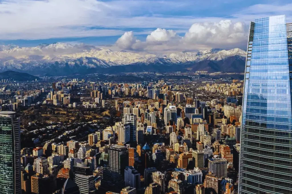 Vista aérea de Santiago do Chile com prédios urbanos e a Cordilheira dos Andes ao fundo, destacando o Costanera Center