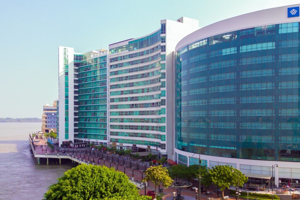 Prédios modernos à beira do rio em Guayaquil, Equador, com arquitetura contemporânea e área urbana revitalizada.