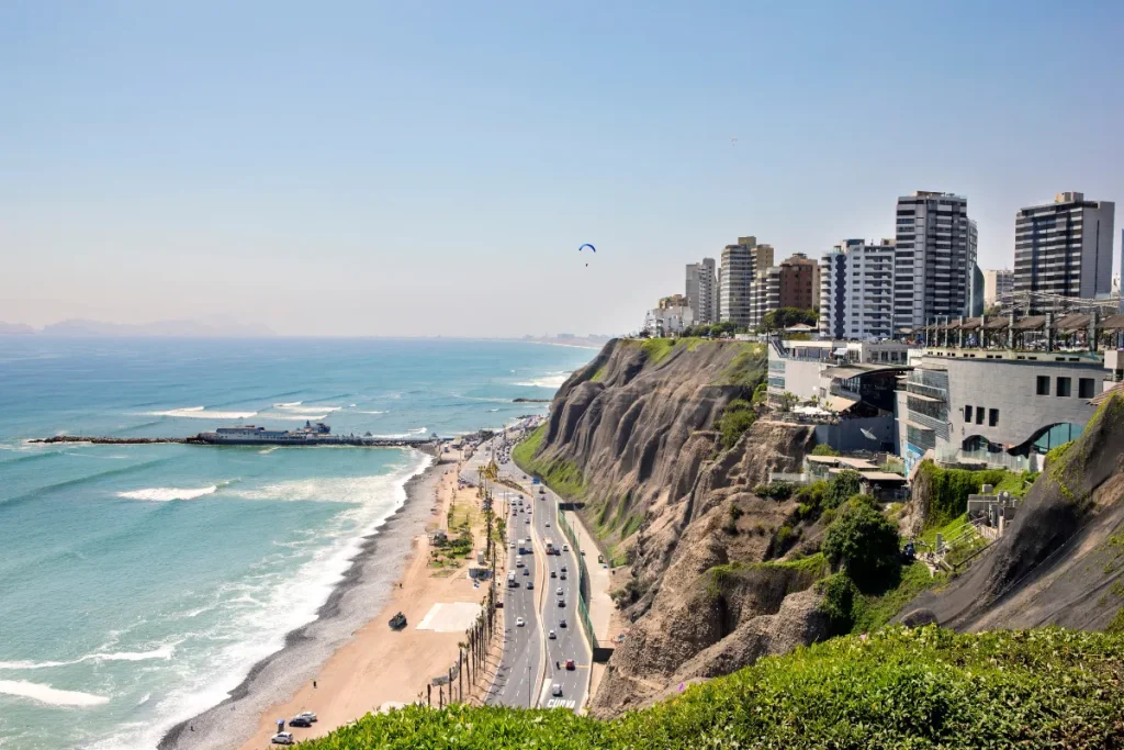 Prédios em cima de morros e, próximo, tem-se uma praia
