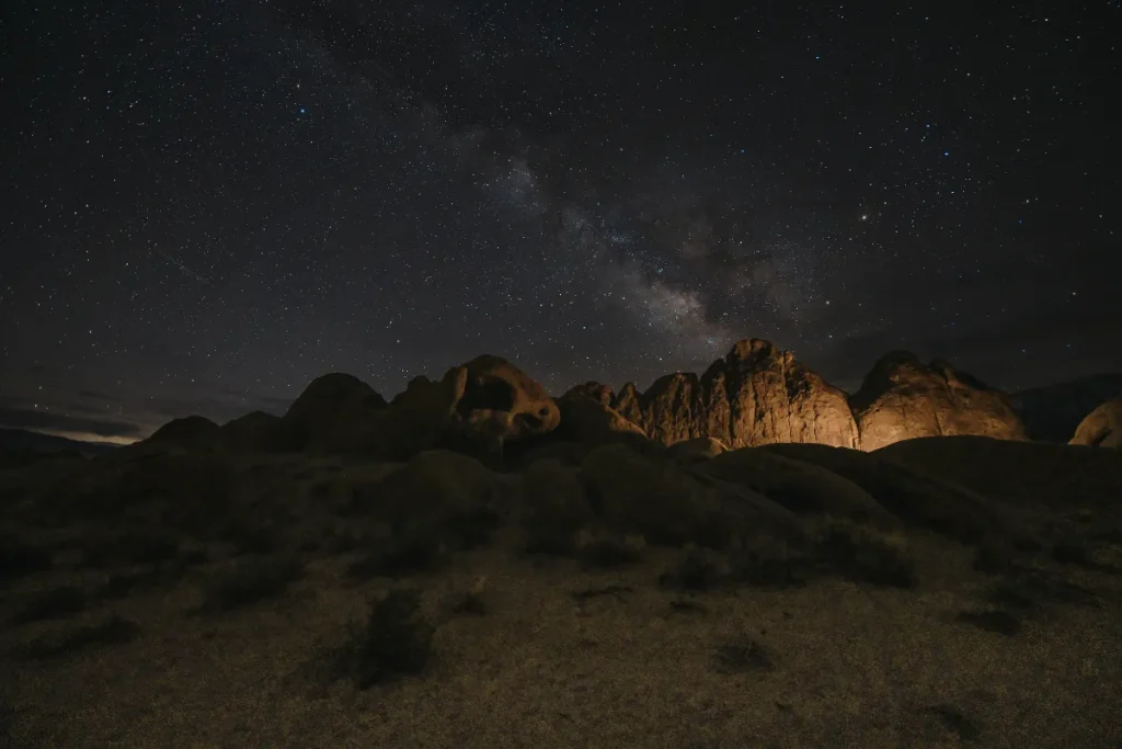 Atacama e tour astronômico. Céu noturno cheio de estrelas e a Via Láctea visível acima de formações rochosas no deserto.