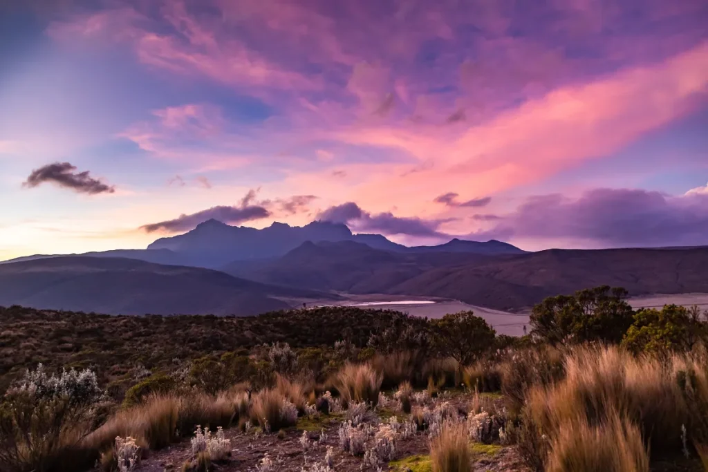Melhor data para o Circuito Andino. Paisagem das montanhas dos Andes ao entardecer com céu colorido em tons de rosa e roxo.