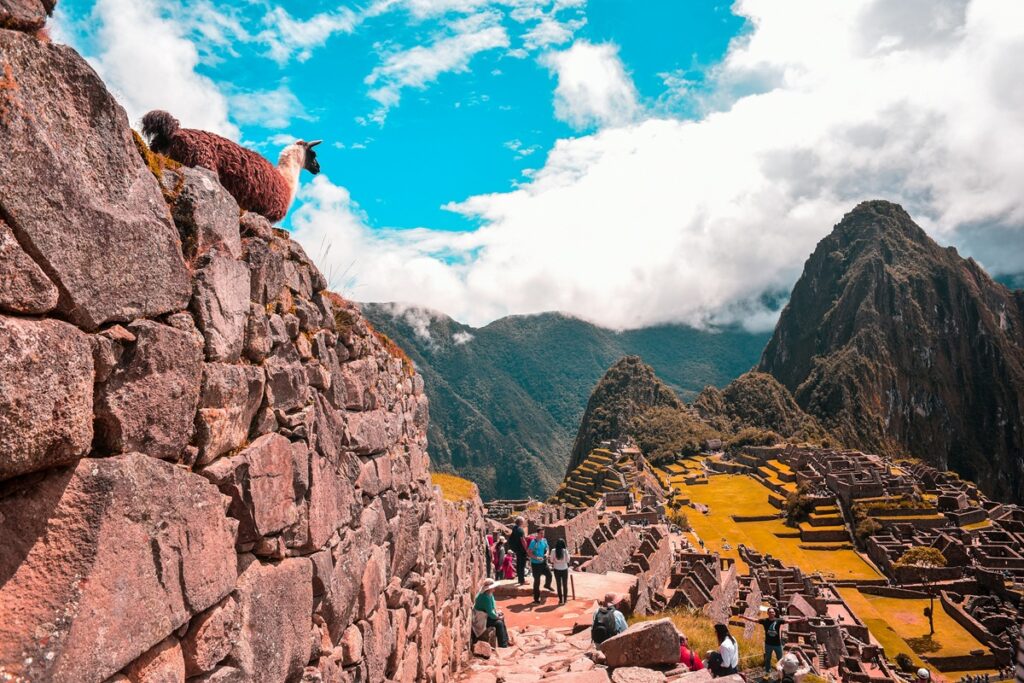 Vista de Machu Picchu com turistas, ruínas incas e montanhas ao fundo.