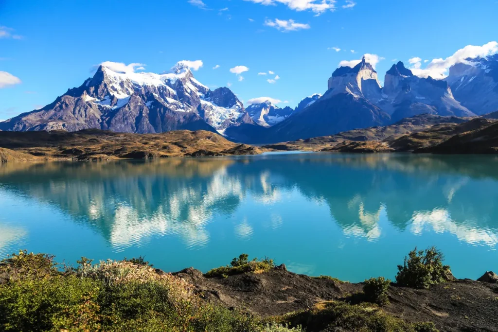 Lago azul refletindo montanhas nevadas no Parque Nacional Torres del Paine, na Patagônia chilena.