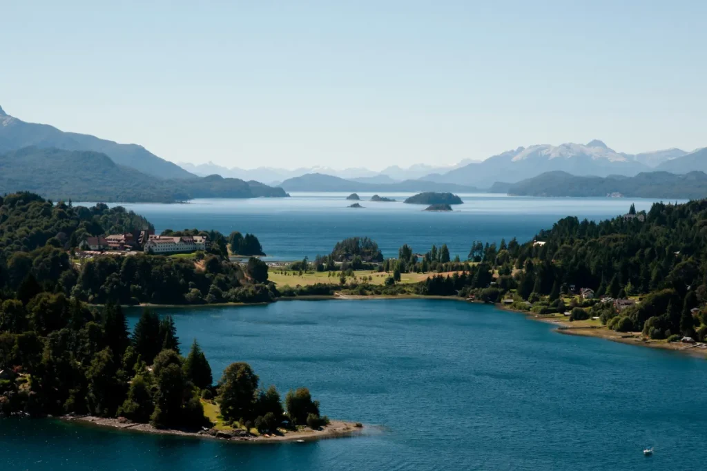Vista panorâmica do lago Nahuel Huapi em Bariloche com ilhas, florestas e montanhas ao fundo.