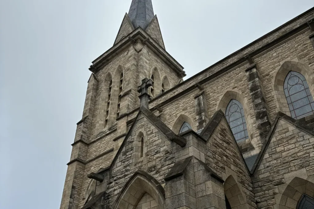 Detalhe da torre e da fachada de pedra da Catedral de Bariloche com janelas góticas.