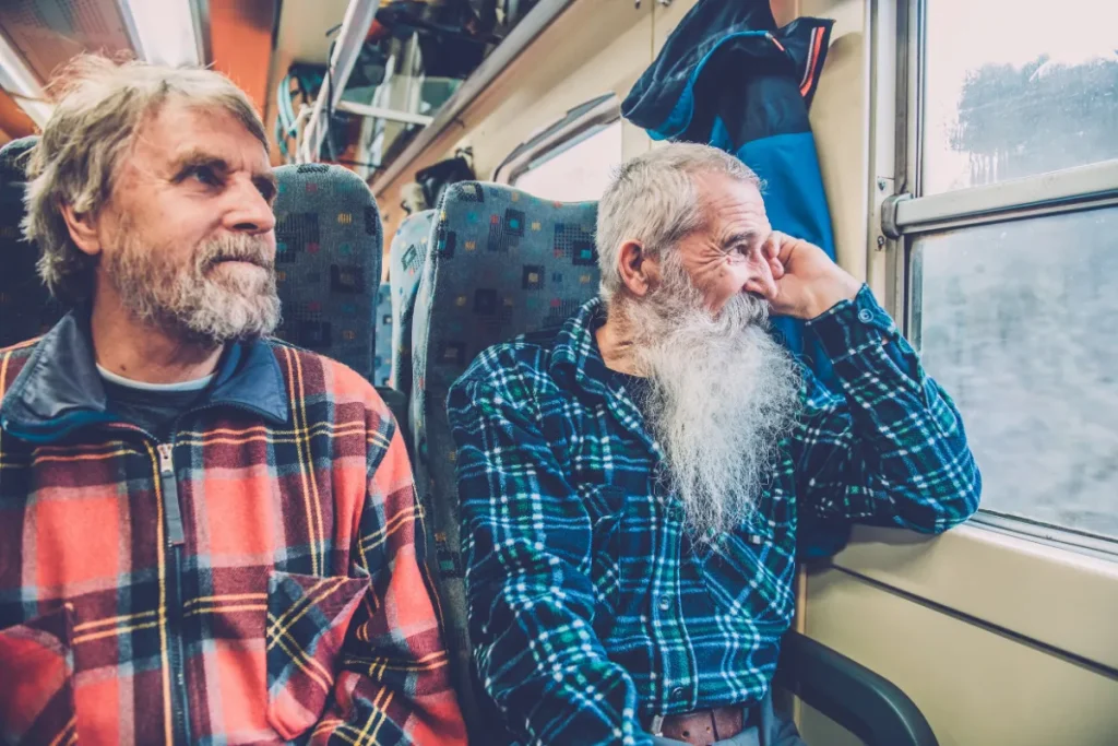 Dois homens idosos sentados em trem olhando pela janela durante a viagem.