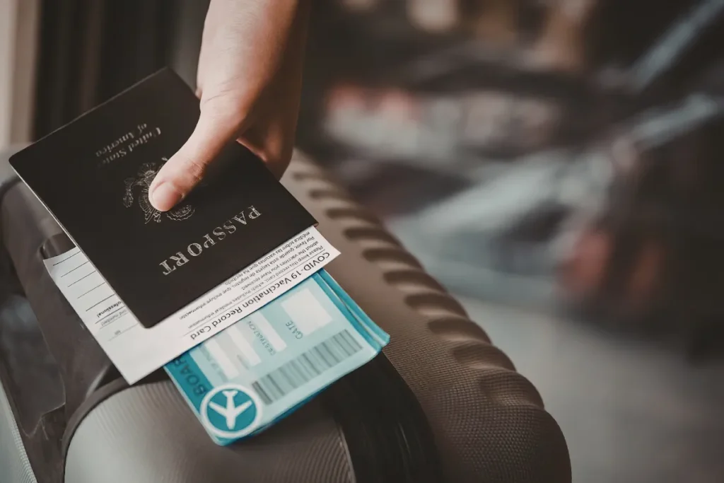 Documentos para viajar para Bariloche. Pessoa segurando passaporte e cartão de embarque sobre mala durante preparação para viagem internacional