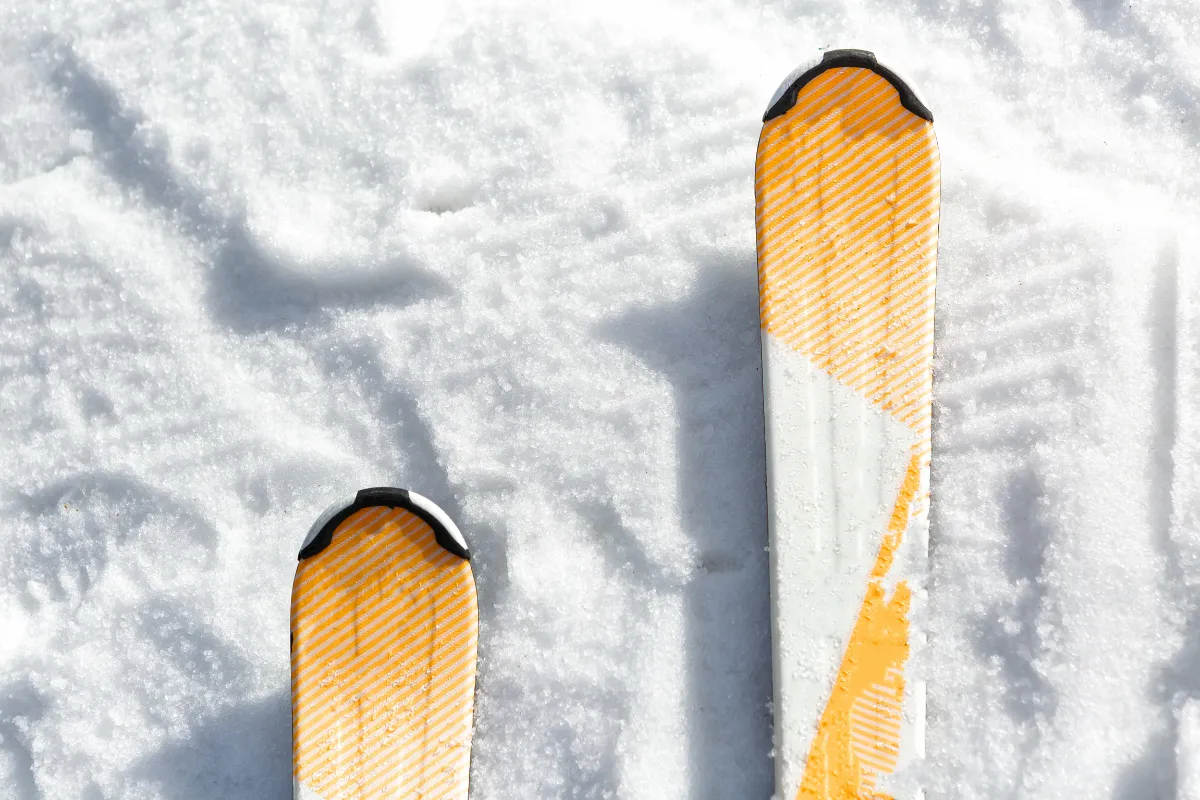 Dois esquis apoiados na neve mostrando parte do equipamento utilizado para praticar esqui.