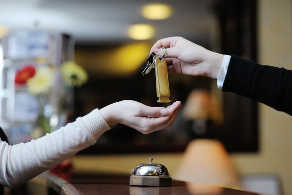 Mãos trocando uma chave de quarto de hotel no balcão da recepção