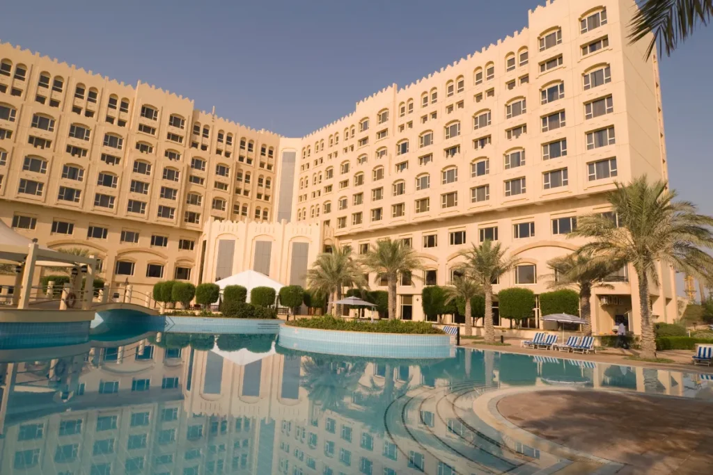 Grande hotel com piscina ao ar livre cercada por palmeiras e espreguiçadeiras