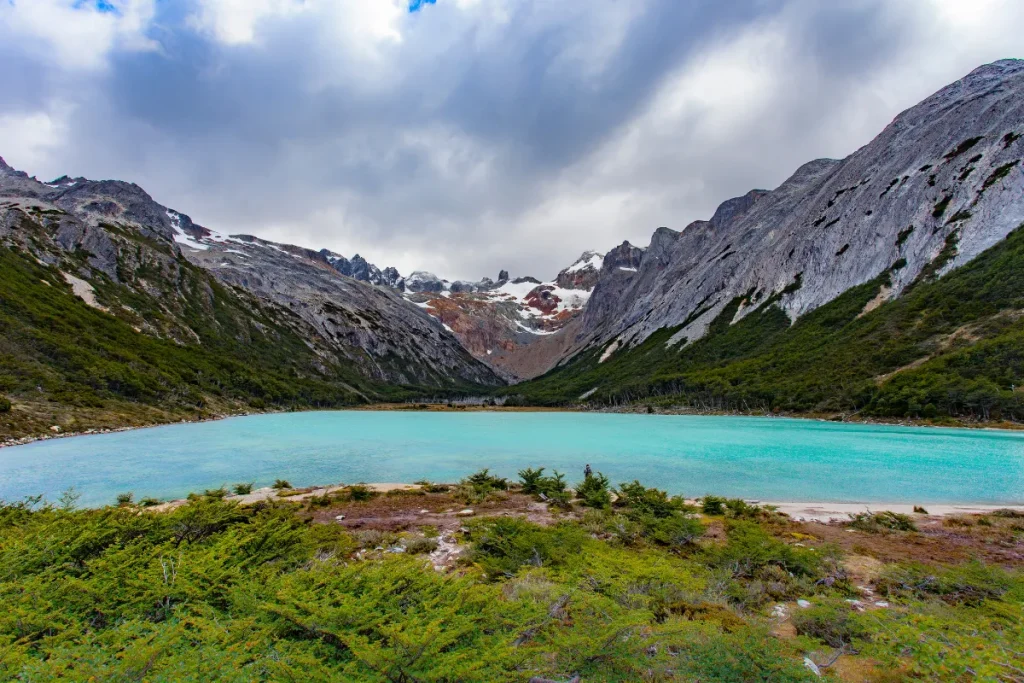 Lago de água turquesa cercado por montanhas e vegetação em Ushuaia