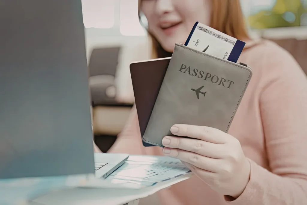Mulher segura passaporte e cartão de embarque em frente ao computador ao organizar documentos para viajar para Bariloche.