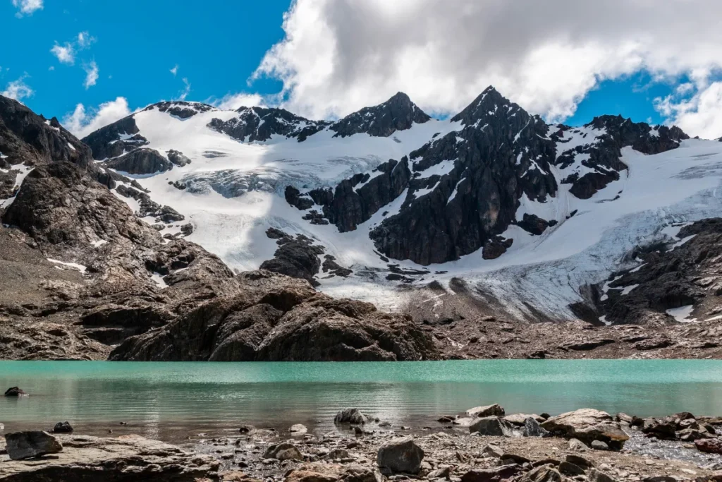 Lago de água azul-esverdeada com glaciar e montanhas nevadas em Ushuaia durante um dos passeios mais procurados da região.