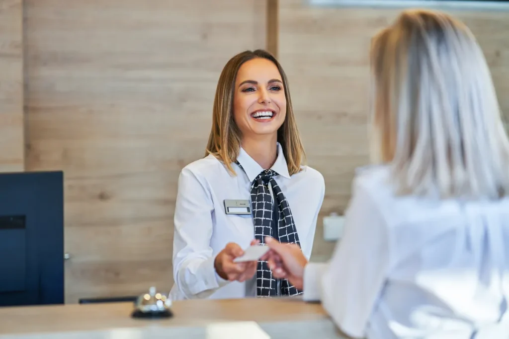 Recepcionista entregando cartão de acesso para hóspede em hotel de Bariloche com atendimento acolhedor.