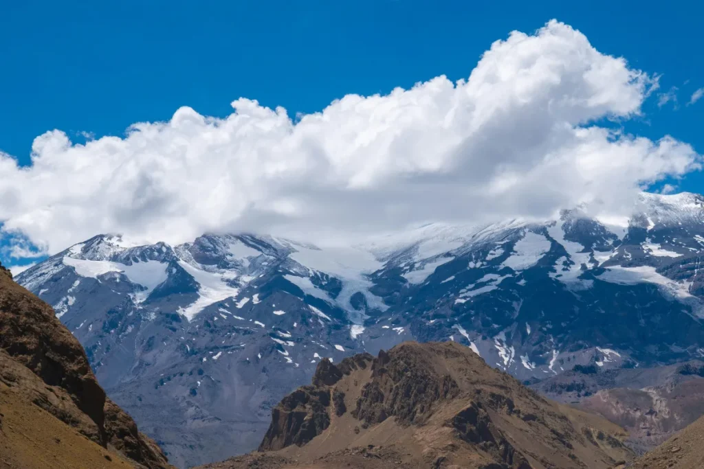 Montanhas da Cordilheira dos Andes com picos nevados e nuvens sobre o topo