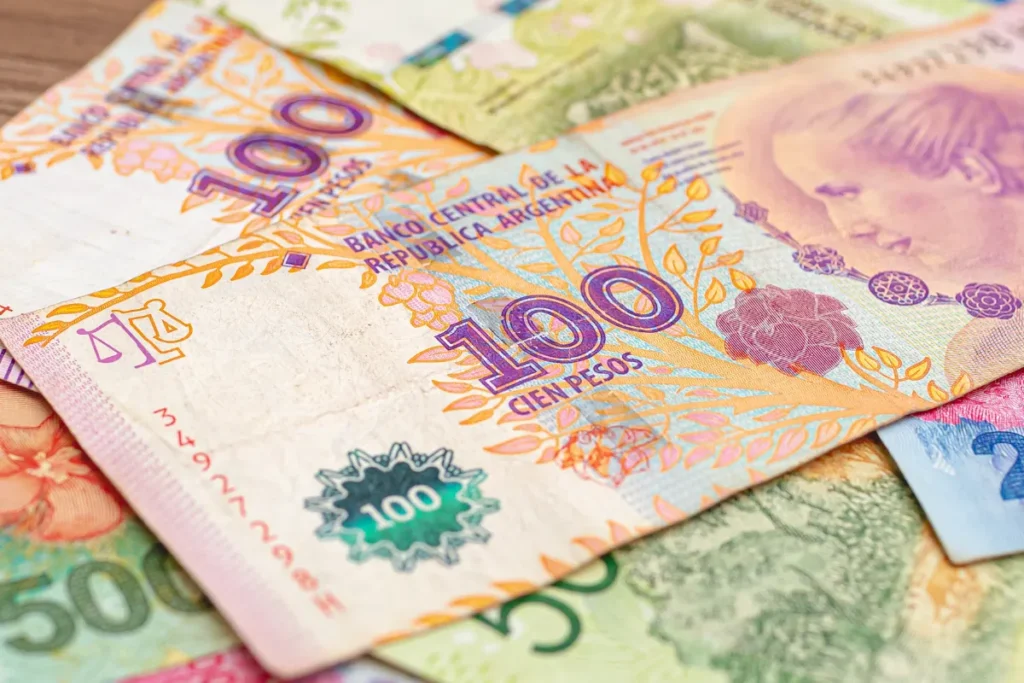 Nota de cem pesos argentinos em destaque entre outras cédulas, representando câmbio e gastos em Bariloche.