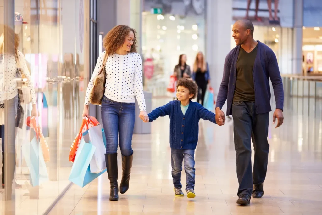 Família caminhando com sacolas em shopping, representando compras no free shop do aeroporto de Bariloche