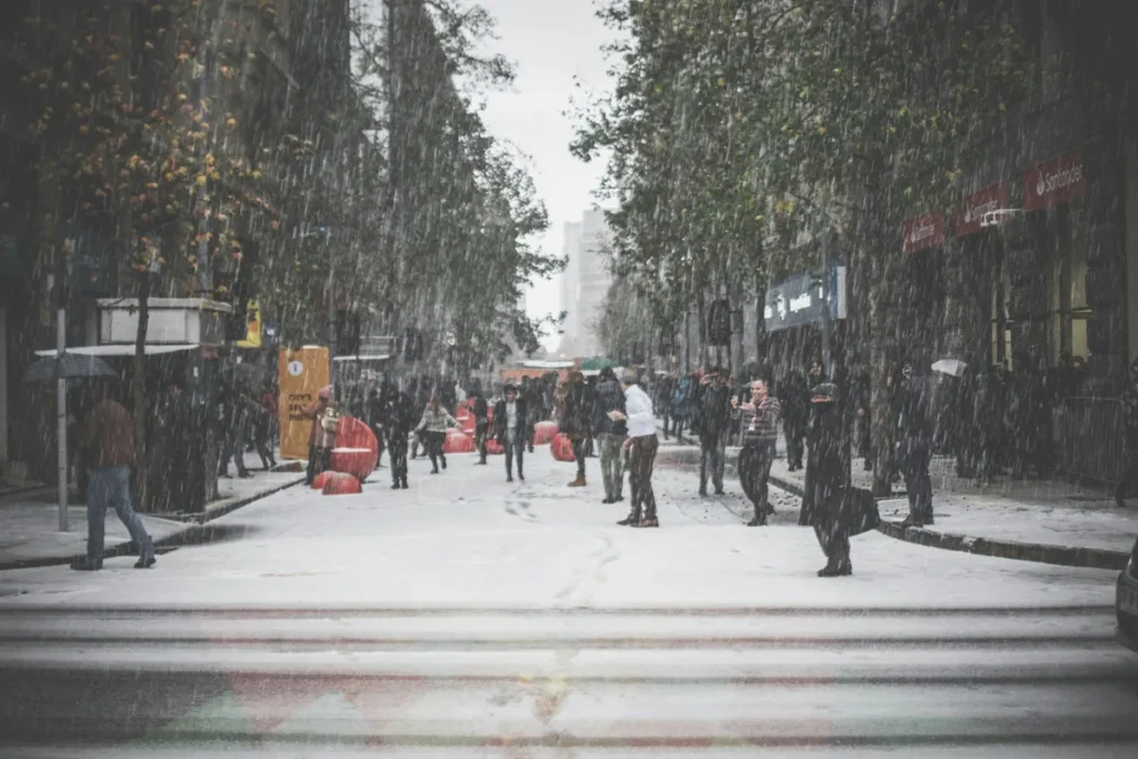 Clima em Santiago: qual a melhor época para conhecer a cidade? Rua movimentada em Santiago do Chile coberta por neve durante forte frio de inverno.