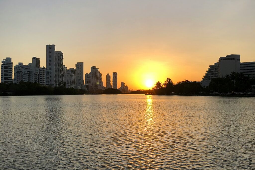 Pôr do sol sobre a baía de Cartagena das Índias com prédios modernos refletidos na água ao entardecer.