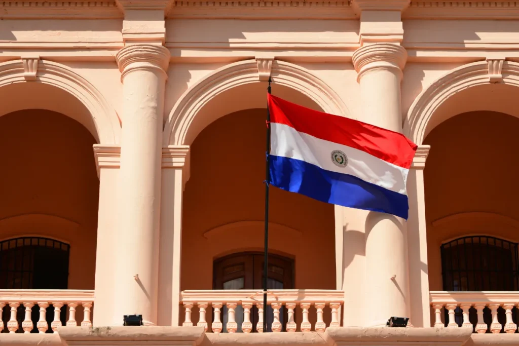 Bandeira do Paraguai em frente à fachada histórica do Palácio de los López, uma das atrações mais visitadas de Assunção.