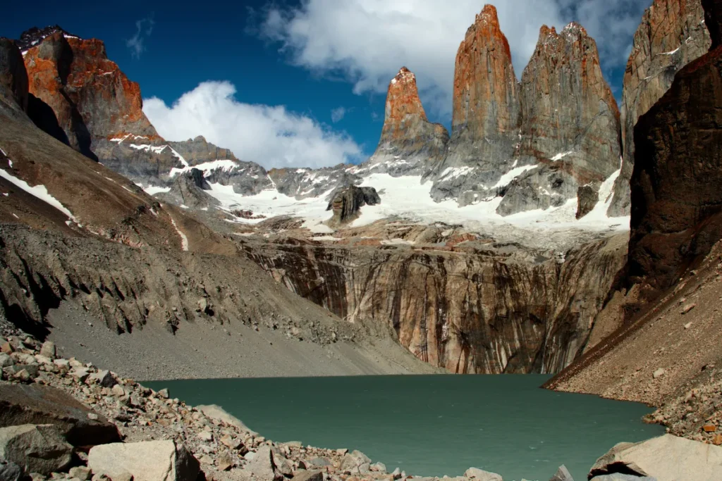 Vista das Torres del Paine com lago glacial azul e montanhas nevadas ao fundo, cenário clássico dos trekkings no Chile.