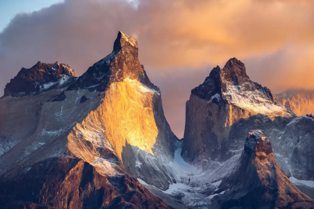 Picos rochosos iluminados pelo pôr do sol em Torres del Paine, destaque natural para trilhas e aventuras na Patagônia.