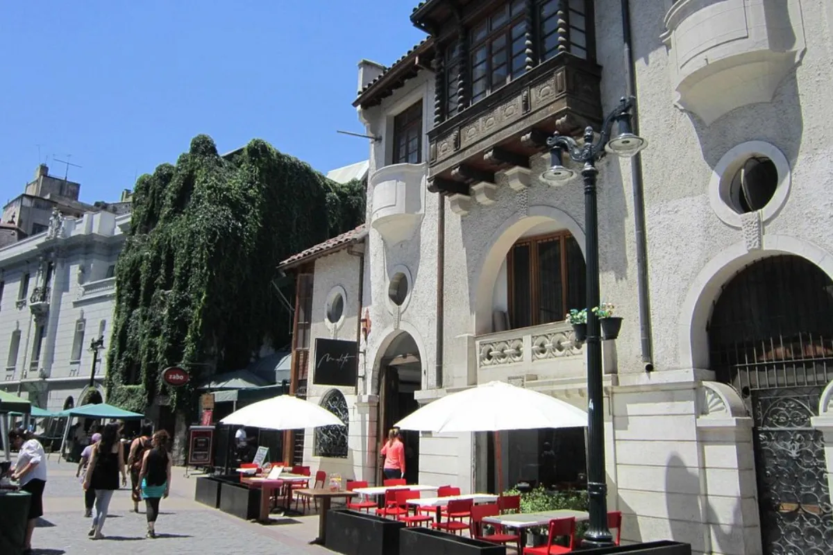 Restaurante com mesas externas na calçada no bairro Lastarria em Santiago, com pessoas caminhando e ambiente turístico