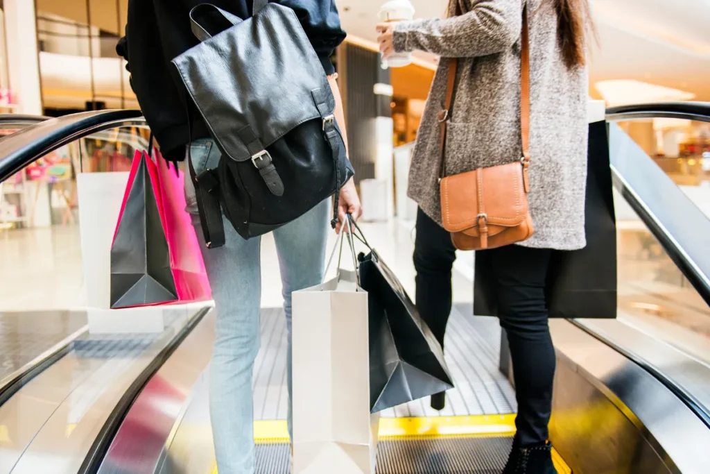 Pessoas subindo escada rolante com sacolas após compras em shopping de Santiago do Chile.